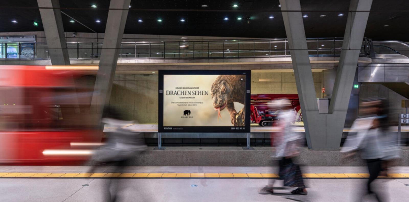 Public-Video-Screen in einer Kölner Bahnstation mit dem Motiv „Drachen sehen leicht gemacht“ des Kölner Zoos